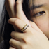 A close-up lifestyle shot of a person wearing a double-band ring on their finger. The ring features a polished gold band on one side and a silver band on the other, both adorned with small clear pavé-set stones.